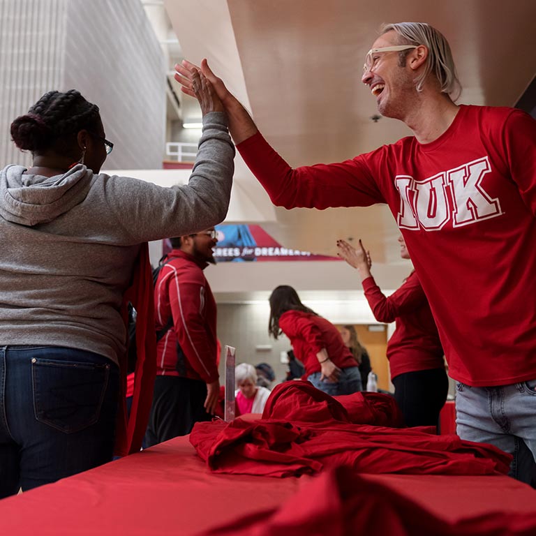 Person wearing an IUK shirt high-fives a student during a giveaway event