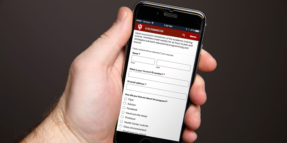 Hand holding phone showing IU website form