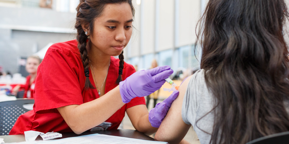 nurse giving student a shot in the arm